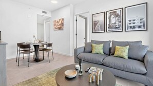 A modern living room with a grey sofa, dining table, and chairs. There are framed pictures on the wall, a coffee table with a bowl and a vase, and a rug on the floor. - Cielo | Downtown Miami Condo,33 FL,  Rooftop Pool, Gym (Miami)