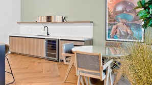 A modern kitchen with a built-in dishwasher, a small dining table with chairs, and a large framed picture on the wall. - Cielo | Downtown Miami Condo,33 FL,  Rooftop Pool, Gym (Miami)