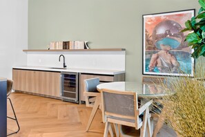 Eine moderne Küche mit eingebautem Geschirrspüler, einem kleinen Esstisch mit Stühlen und einem großen, gerahmten Bild an der Wand.
