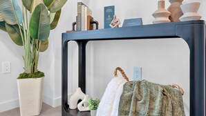 A room with a black console table, a potted plant, a television mounted on the wall, and a few decorative items. - Cielo | Downtown Miami Condo,33 FL,  Rooftop Pool, Gym (Miami)