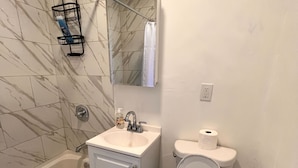 Uma casa de banho com banheira, lavatório, sanita e zona de duche.
