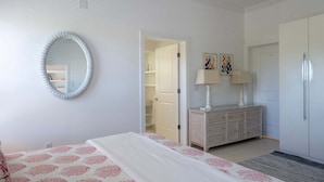 Ein Schlafzimmer mit einem Bett, einem Schminktisch, einem Spiegel und einer Tür zu einem Badezimmer.