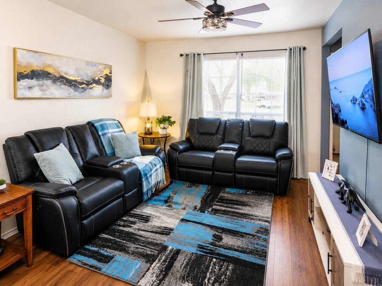 A living room with a sofa, a recliner, a TV, and a painting on the wall.