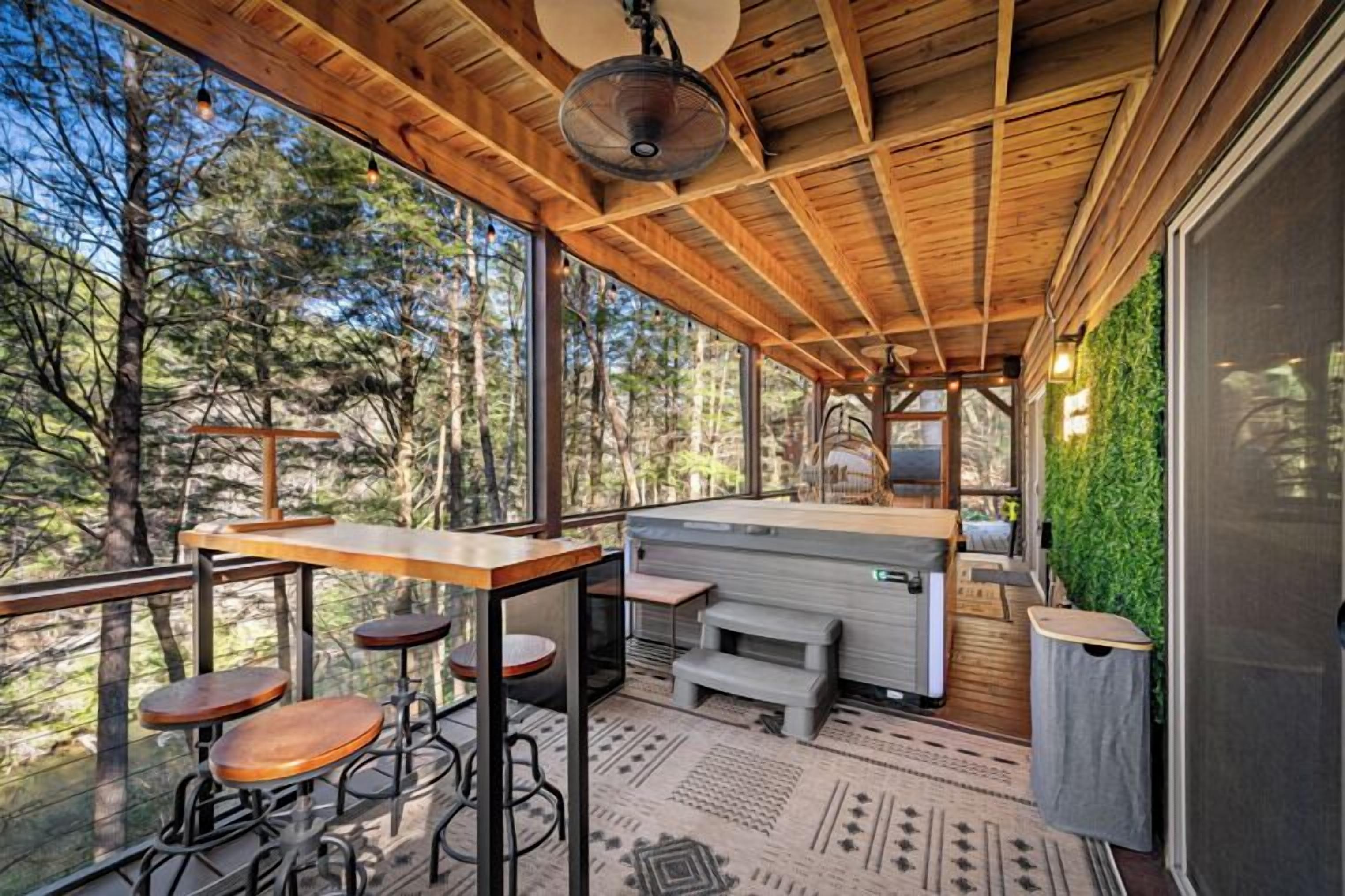 A wooden deck with a bar area, seating, and a view of the forest.