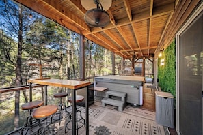 Une terrasse en bois avec un bar, des sièges et une vue sur la forêt.