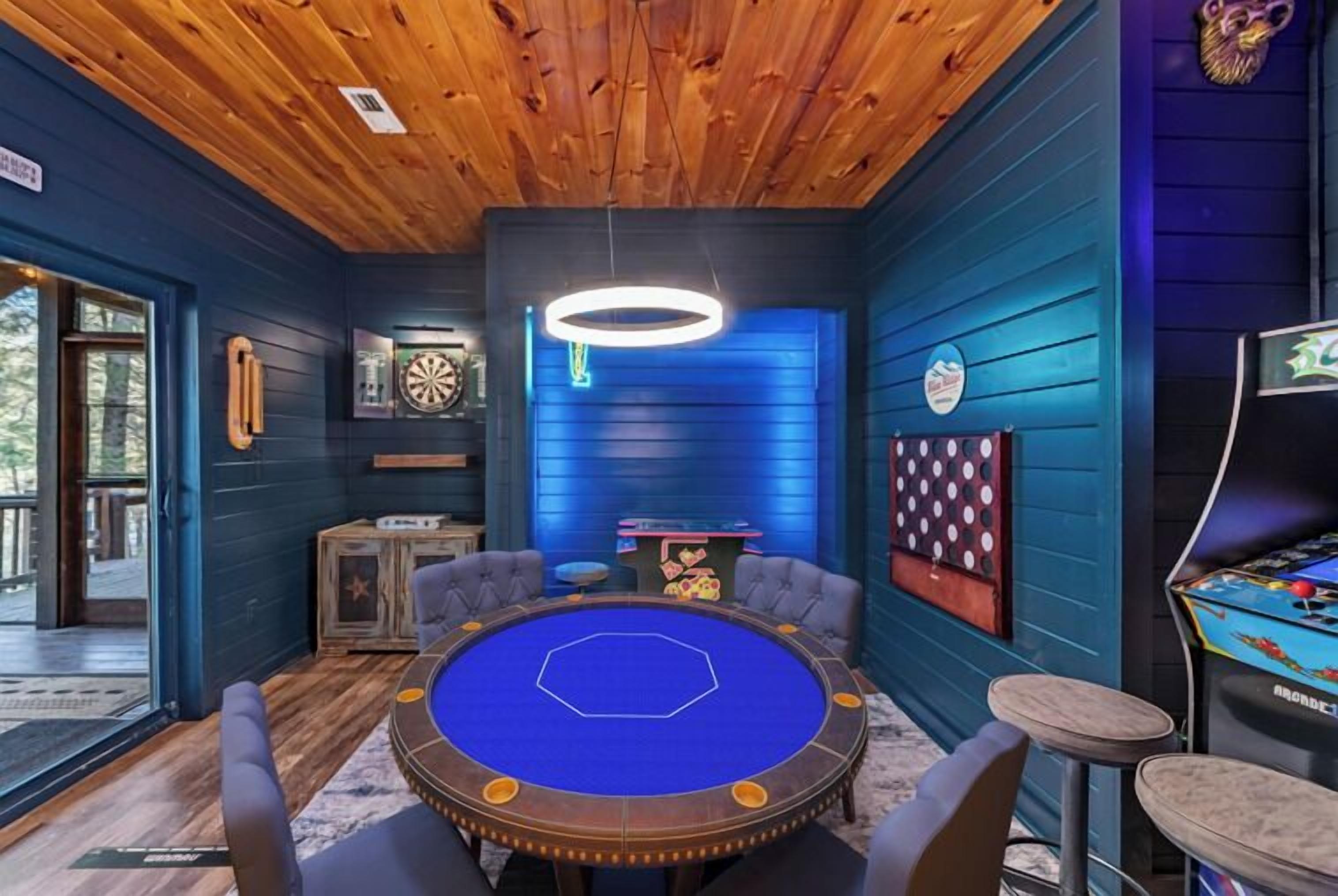 A room with a pool table, dartboard, and pinball machine.
