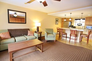 A living room with a sofa, armchairs, a coffee table, a dining area with chairs, a kitchen with a refrigerator, and a ceiling fan. - Leaf Peep at Pollard Brook! (Lincoln)
