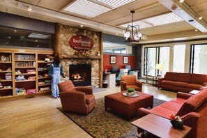 A hotel lobby with a fireplace, seating area, and a bookshelf. - Leaf Peep at Pollard Brook! (Lincoln)