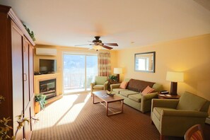 Ein Wohnzimmer mit Sofa, Sessel, Couchtisch, Fernseher, Kamin und Deckenventilator.