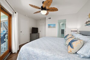 Ein Schlafzimmer mit Bett, Deckenventilator, Fernseher und Kunstwerk an der Wand.