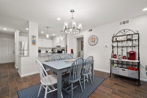 A modern kitchen with white cabinets, a stainless steel refrigerator, and a dining area with a table and chairs. - Gulf-view 1BR condo at La Mirage with pool, hot tub, and beach access. (Port Aransas)