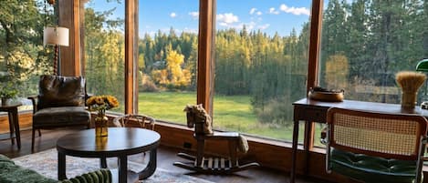 A spacious room with large windows, a leather chair, a dining table, and a green sofa.