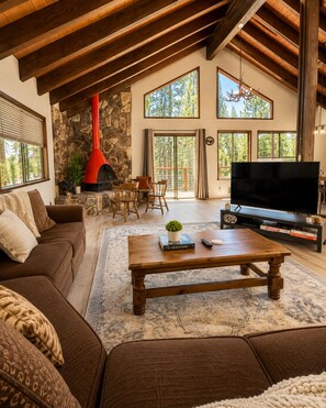 Un salón amplio con chimenea de piedra, un televisor de pantalla plana grande y una zona de estar acogedora.