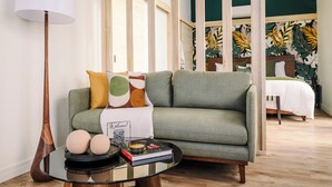 Een moderne woonkamer met een groene bank, een ronde salontafel en een lamp.