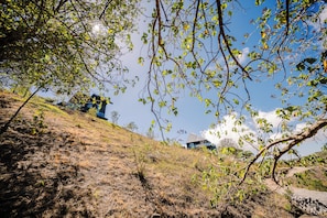 A hillside with sparse vegetation and a modern building with a sloped roof.