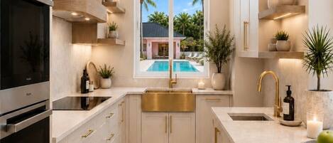 Cocina moderna con un ventanal grande, horno empotrado y vista a una piscina.
