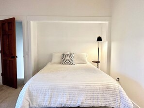 A bedroom with a bed, two pillows, a bedside lamp, and a door. - 2BR/2BA Whitefish Lake Overlook at Suncrest (Whitefish)