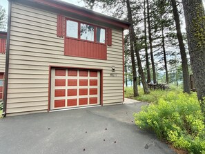 A two-story building with a garage, surrounded by trees and a small deck. - 2BR/2BA Whitefish Lake Overlook at Suncrest (Whitefish)