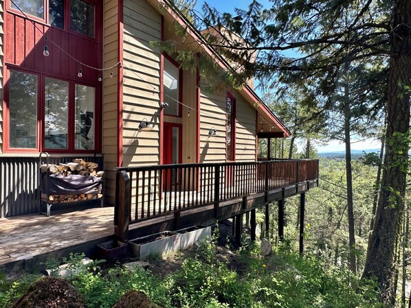 A two-story wooden cabin with a balcony, surrounded by forest. - 2BR/2BA Whitefish Lake Overlook at Suncrest (Whitefish)