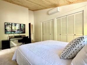 A bedroom with a bed, a desk, a chair, a TV, and a wardrobe. - 2BR/2BA Whitefish Lake Overlook at Suncrest (Whitefish)