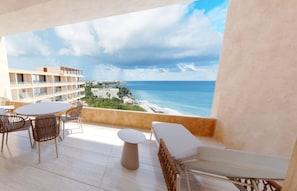 A balcony with a view of the sea and buildings, furnished with white chairs and a table. - Inna Resort & Spa (Puerto Morelos)