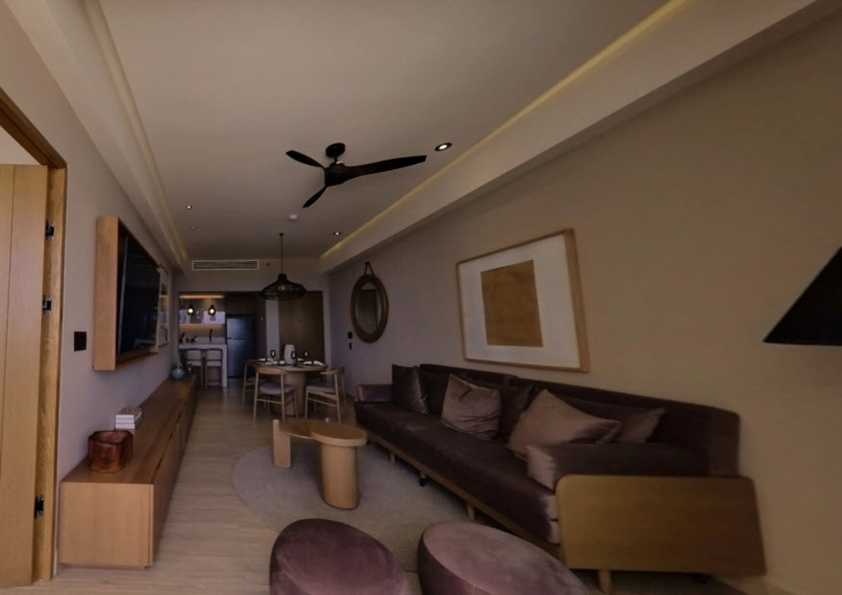 A modern living room with a sofa, a coffee table, and a dining area in the background.