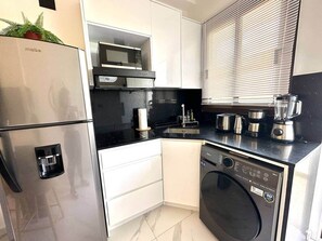 A compact kitchen with a refrigerator, microwave, stove, and dishwasher. - Cana Life Luxury | Cana Rock Universe Pool View (Punta Cana)