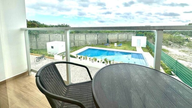 Un balcon donnant sur une piscine, avec une table et des chaises.