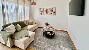 Un salon avec un canapé, une table basse et un téléviseur fixé au mur.