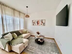Ein Wohnzimmer mit einer Couch, einem Couchtisch und einem an der Wand befestigten Fernseher.