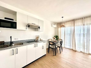Et moderne køkken med hvide skabe, en granitbordplade og et spiseområde med et bord og stole.