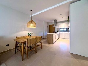 Uma cozinha moderna com armários brancos, uma ilha de madeira e uma luminária pendente.