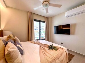 Une chambre d’hôtel avec un lit, un ventilateur de plafond, un téléviseur à écran plat et une fenêtre avec des rideaux.