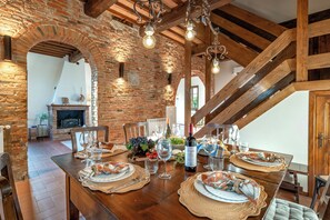 Ein rustikaler Essbereich mit Holztisch, gedeckten Plätzen, Backsteinwänden und freiliegenden Holzbalken.