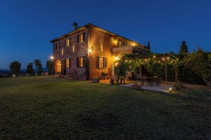 Ein zweigeschossiges Backsteinhhaus mit Balkon, Sitzgelegenheiten im Freien und Lichterketten.