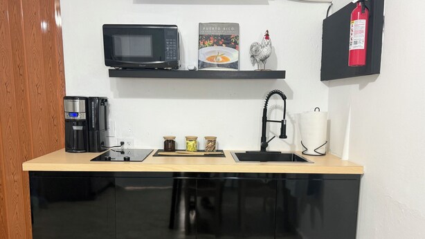 Eine Küche mit Mikrowelle, Kaffeemaschine und Gläsern auf der Arbeitsplatte.