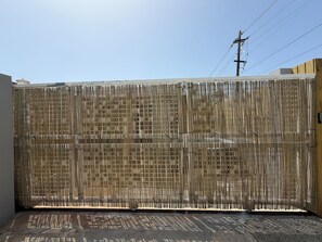 A bamboo fence with vertical slats, a concrete floor, and a power line in the background. - Description (Fajardo)