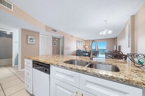 A modern kitchen with granite countertops, white cabinetry, and a stainless steel sink. - Gulf Shores Plantation Palms 6603 | Pool + Hot Tub (Gulf Shores)