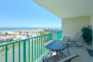 A balcony with a view of the beach, a pool, and hotel buildings. - Gulf Shores Plantation Palms 6603 | Pool + Hot Tub (Gulf Shores)