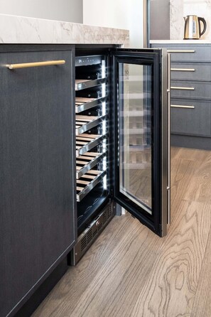 A modern kitchen with a built-in refrigerator, wooden flooring, and a marble countertop. - The Aqua Collection - Lakeview Terrace - 902 (Kelowna)