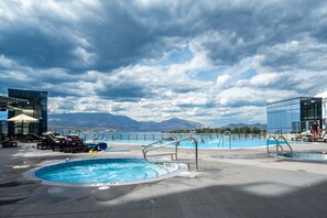 A rooftop pool with lounge chairs, a hot tub, and a view of mountains. - The Aqua Collection - Lakeview Terrace - 902 (Kelowna)