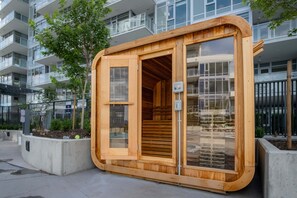 A wooden structure with a door and windows, situated in an urban setting with modern buildings in the background. - The Aqua Collection - Lakeview Terrace - 902 (Kelowna)
