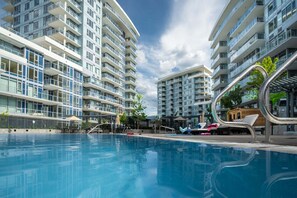 A modern residential building with a swimming pool, balconies, and a clear sky. - The Aqua Collection - Lakeview Terrace - 902 (Kelowna)