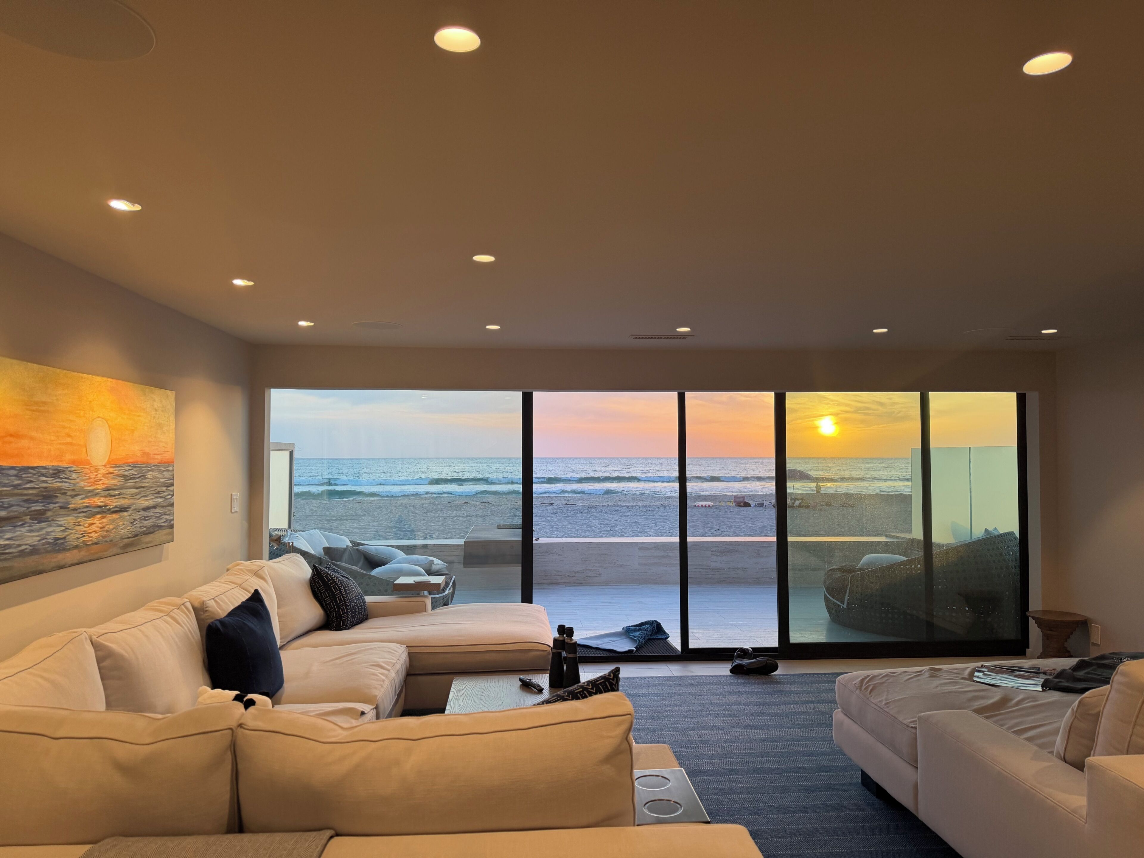 A modern living room with a large sliding glass door leading to a beach view.
