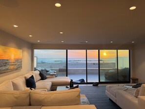 A modern living room with a large sliding glass door leading to a beach view. - Fabulous 2-bedroom oceanfront estate with AC in sunny Del Mar (Del Mar)