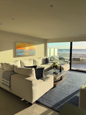 A modern living room with a sofa, coffee table, and a painting of a sunset. - Fabulous 2-bedroom oceanfront estate with AC in sunny Del Mar (Del Mar)