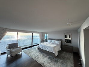 A modern bedroom with a large bed, a seating area, and a view of the ocean. - Fabulous 2-bedroom oceanfront estate with AC in sunny Del Mar (Del Mar)