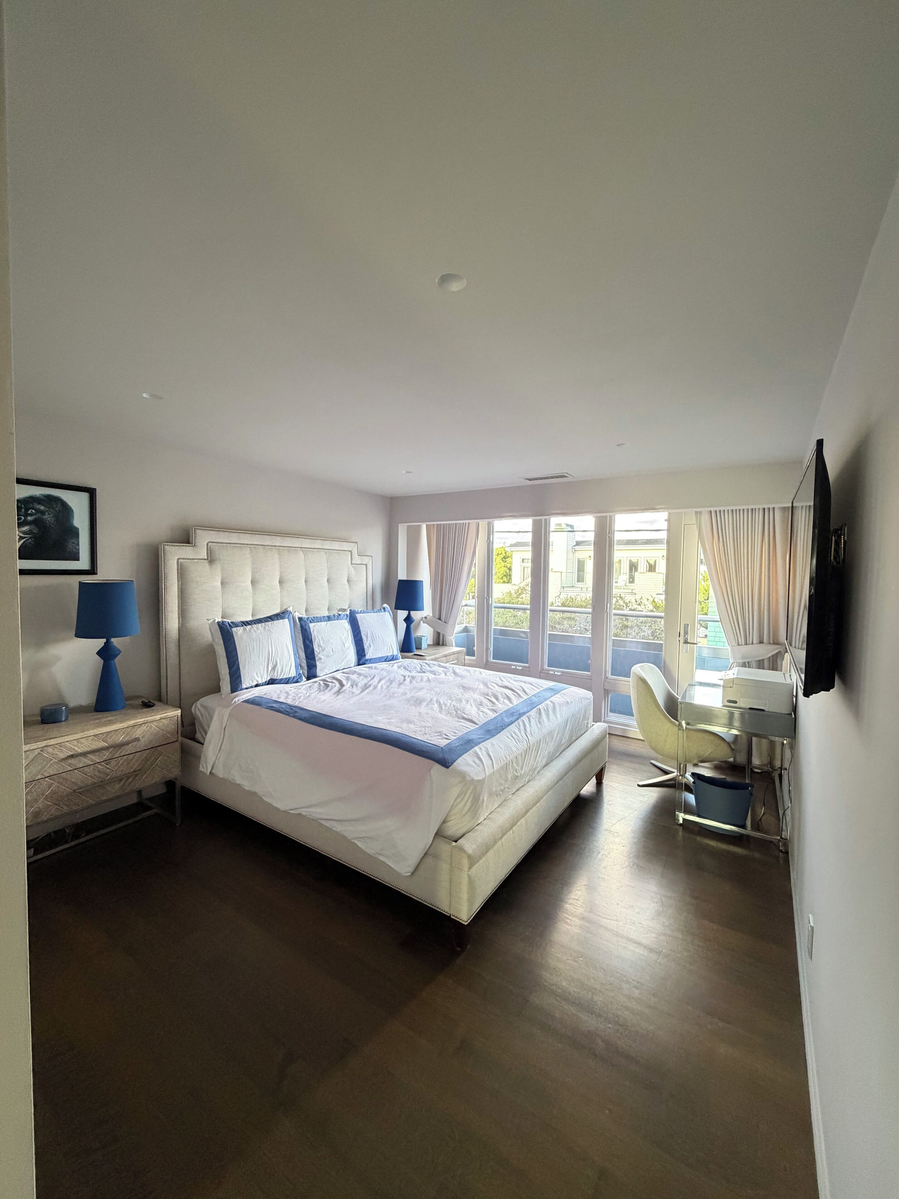 A modern bedroom with a large bed, bedside tables, a desk, and a chair.