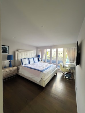 Een moderne slaapkamer met een groot bed, nachtkastjes, een bureau en een stoel.