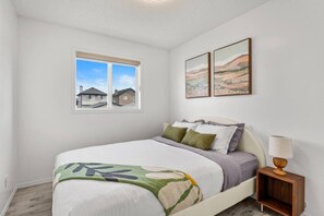 Un dormitorio con cama, ventana con vistas y dos cuadros en la pared.